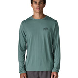 Man wearing Patagonia's men's capilene cool daily long sleeve t-shirt in sage blue with black mountain graphic on upper chest