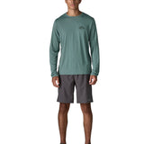 Man wearing Patagonia's men's capilene cool daily long sleeve t-shirt in sage blue. T-shirt has a relaxed and sits around the hips