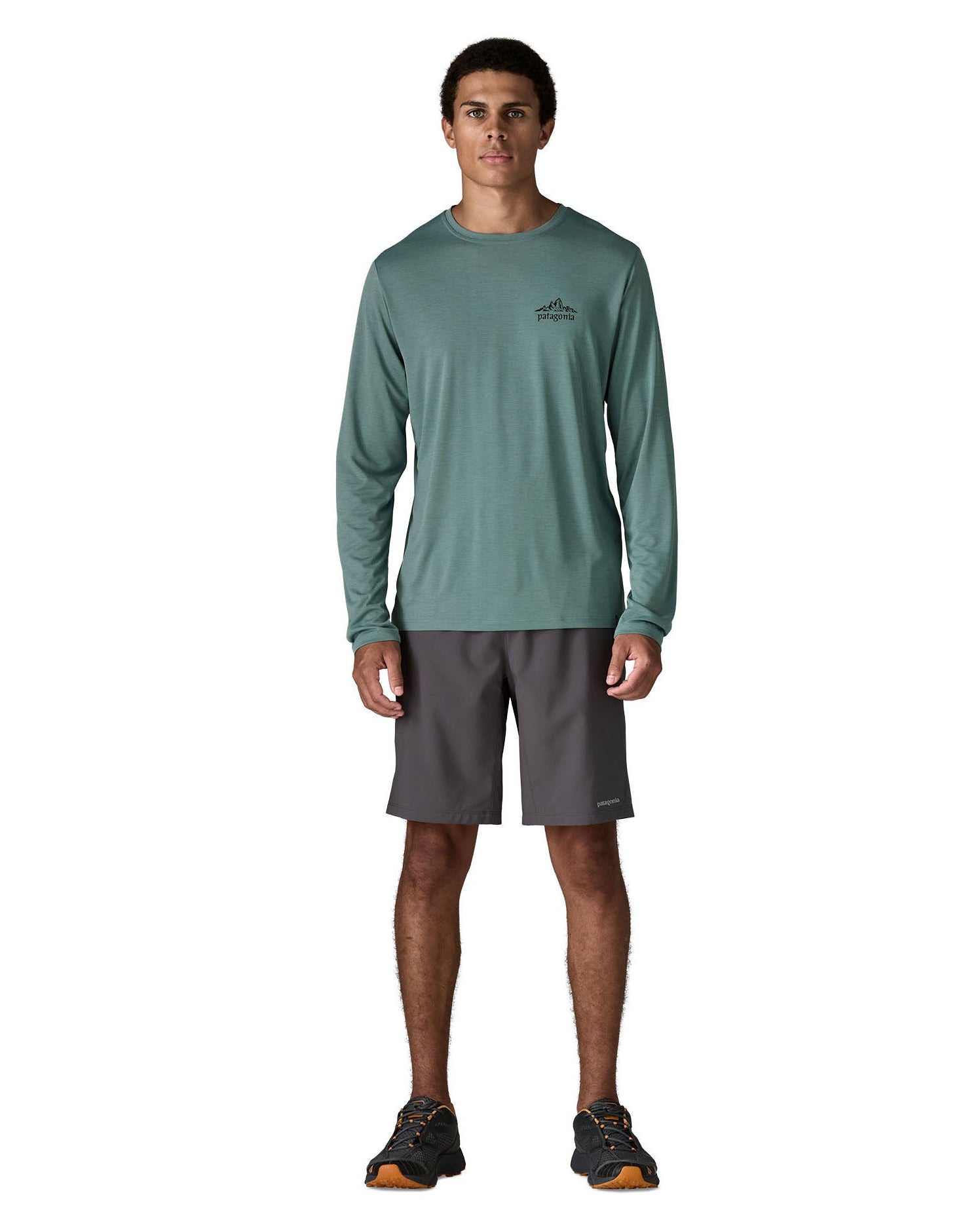 Man wearing Patagonia's men's capilene cool daily long sleeve t-shirt in sage blue. T-shirt has a relaxed and sits around the hips