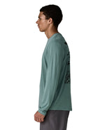 Side of man Patagonia men's capilene cool daily long sleeve t-shirt in sage blue. T-shirt has a relaxed and sits around the hips