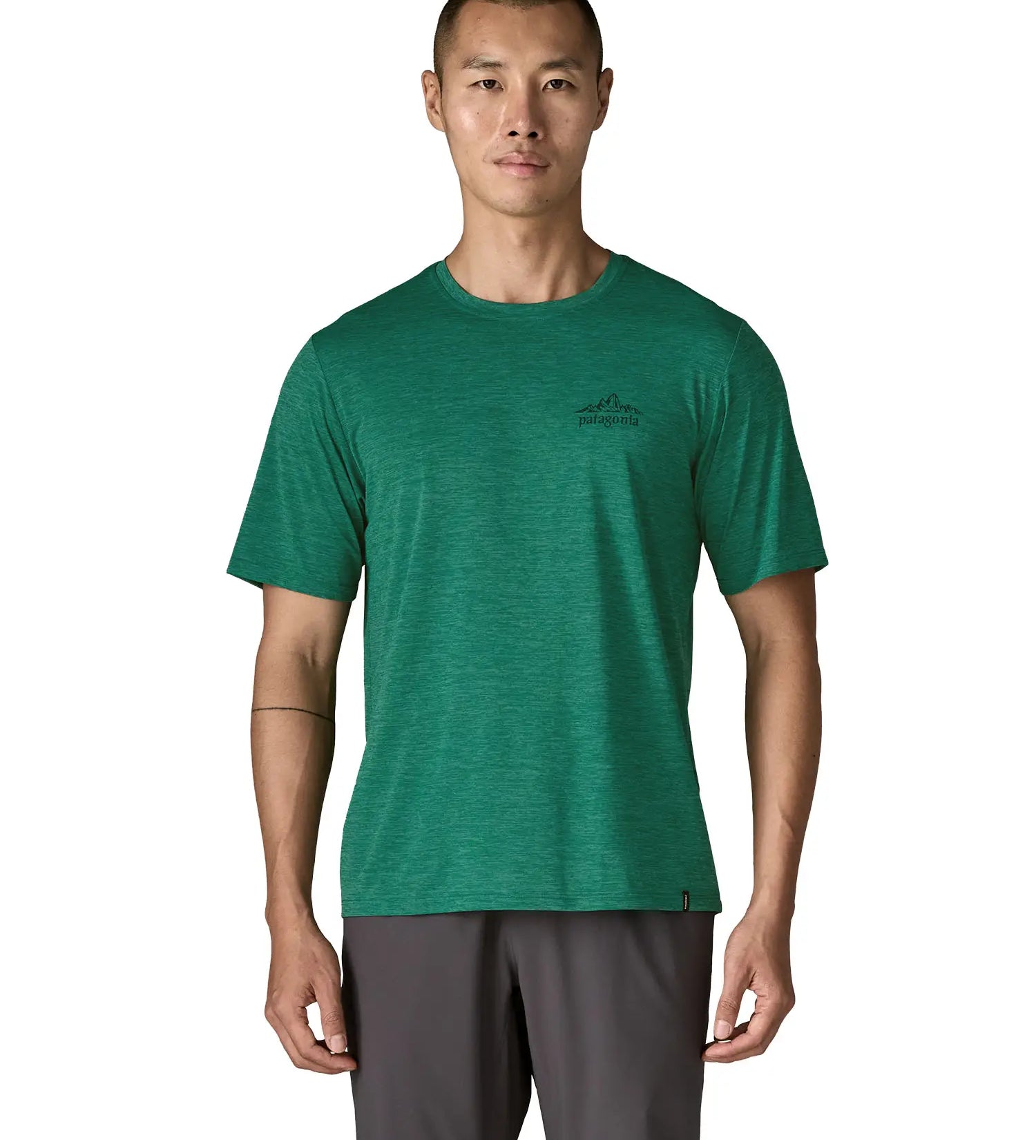 Man wearing Patagonia men's capilene cool daily short sleeve t-shirt in green with small mountain outline graphic on the chest