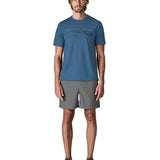 Man wearing Patagonia men's capilene trail short sleeve t-shirt in blue with mountain outline graphic on upper body. T-shirt has a relaxed fit and sits at the hips