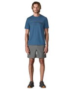 Man wearing Patagonia men's capilene trail short sleeve t-shirt in blue with mountain outline graphic on upper body. T-shirt has a relaxed fit and sits at the hips
