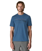 Man wearing Patagonia men's capilene trail short sleeve t-shirt in blue with mountain outline graphic on upper body