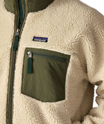A close up of the Patagonia classic retro x jacket in natural/green available at Babipur showing the green chest pocket panel detail