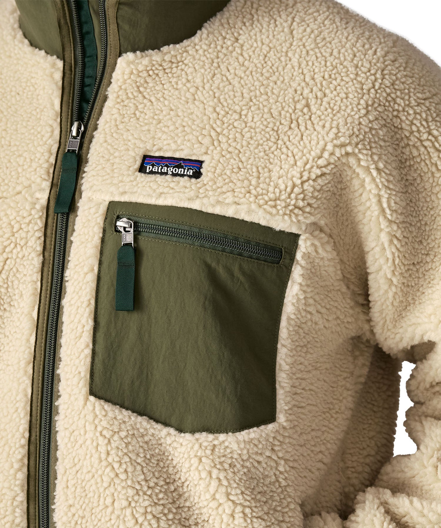 A close up of the Patagonia classic retro x jacket in natural/green available at Babipur showing the green chest pocket panel detail