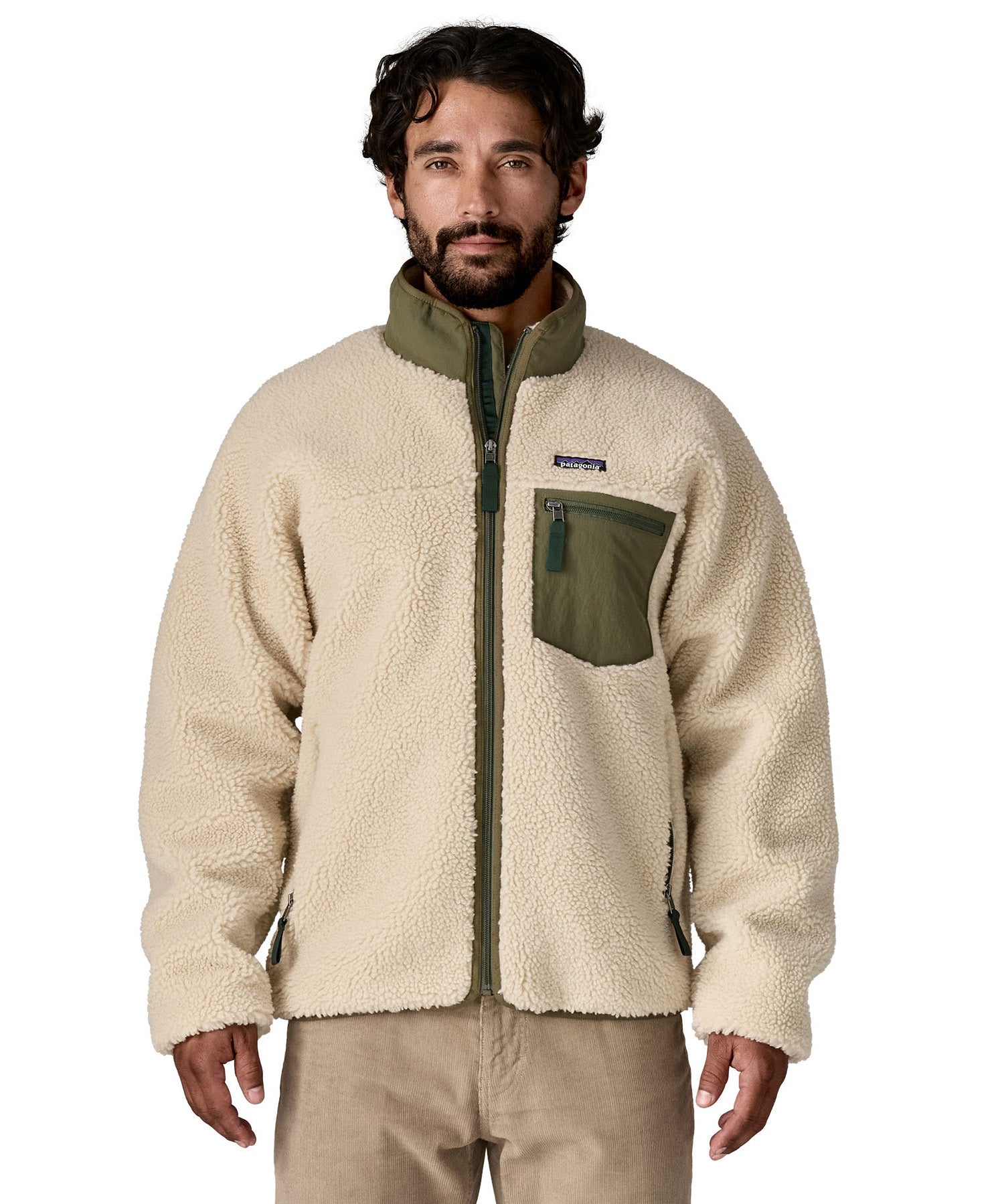 A man wearing the Patagonia classic retro x jacket in natural/green available at Babipur. A thick fleece jacket in beige colour with a green trim, features a full length zip.turn up collar anda chest pocket.