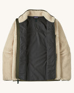 An open Patagonia men's thick fleece jacket in a cream colour showing the dark blue inner lining and fleece collar.