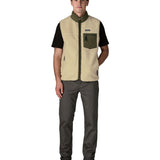 Man wearing Patagonia's classic retro x warm fleece vest in beige with green trim with full front zip fastened. Gilet has a regular fit