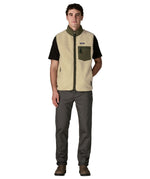 Man wearing Patagonia's classic retro x warm fleece vest in beige with green trim with full front zip fastened. Gilet has a regular fit