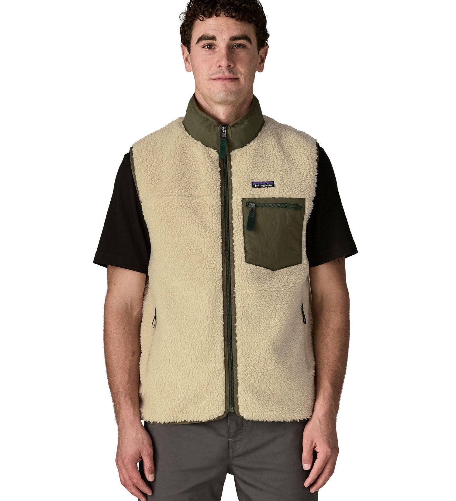 Man wearing Patagonia's classic retro x warm fleece vest in beige with green trim showing full front zip, turned up collar, chest and side pockets
