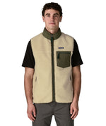 Man wearing Patagonia's classic retro x warm fleece vest in beige with green trim showing full front zip, turned up collar, chest and side pockets
