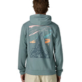 Back of man wearing a Patagonia cloud crag daily hoody in sage blue showing a large minimalistic geometric style print of a mountain ridge. Hoodie has a relaxed fit