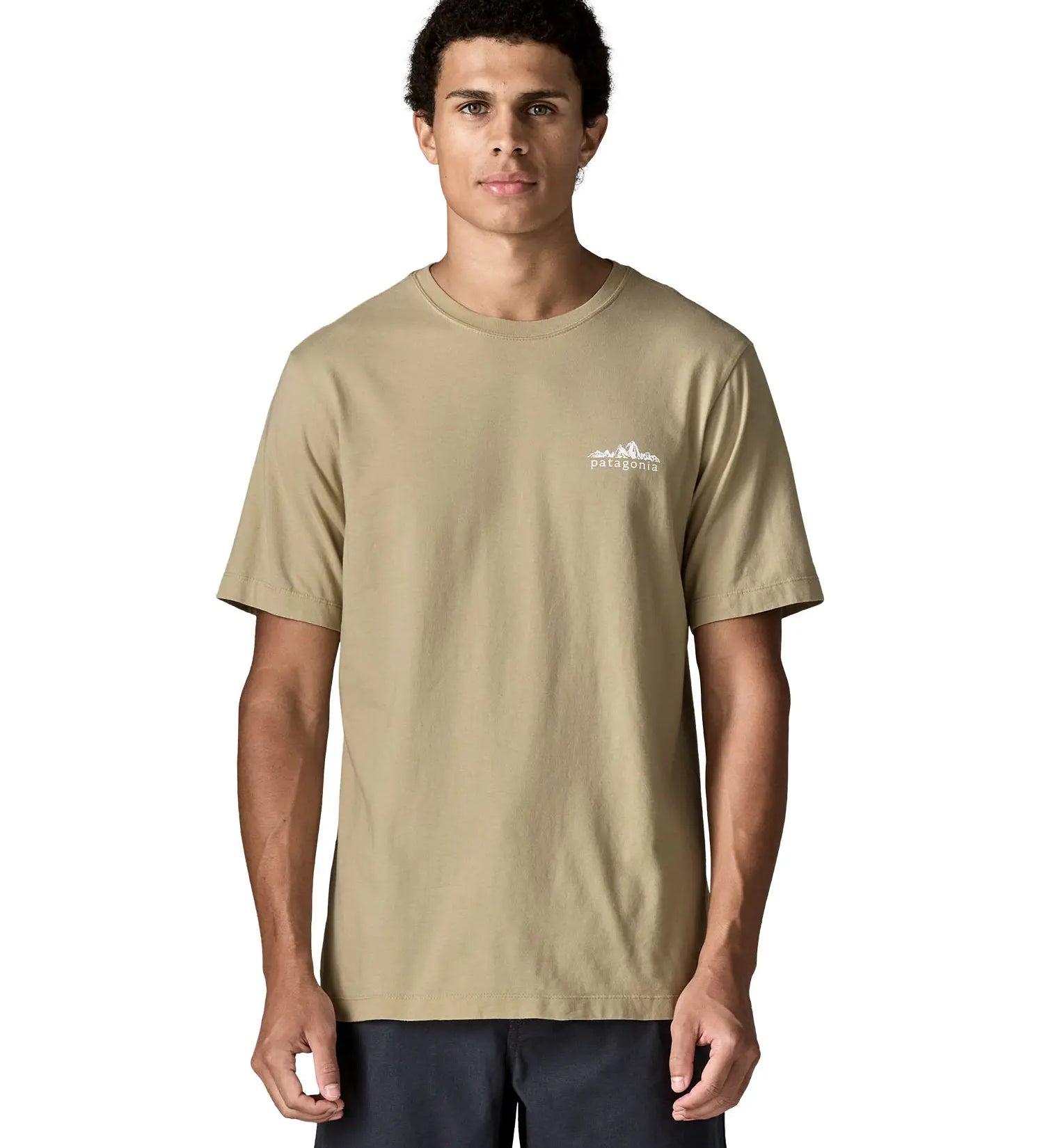Man wearing Patagonia's  fitz roy foothills short sleeve t-shirt in beige showing a small mountain branded print on the upper chest. Top has a relaxed fit
