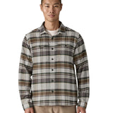  A man wearing the Patagonia fjord flannel shirt in blizzard/salt grey available at Babipur. A thick fleece in a grey and brown chequered design. Features button fasteners and 2 chest pockets 