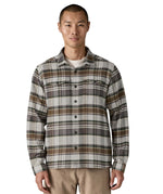  A man wearing the Patagonia fjord flannel shirt in blizzard/salt grey available at Babipur. A thick fleece in a grey and brown chequered design. Features button fasteners and 2 chest pockets 