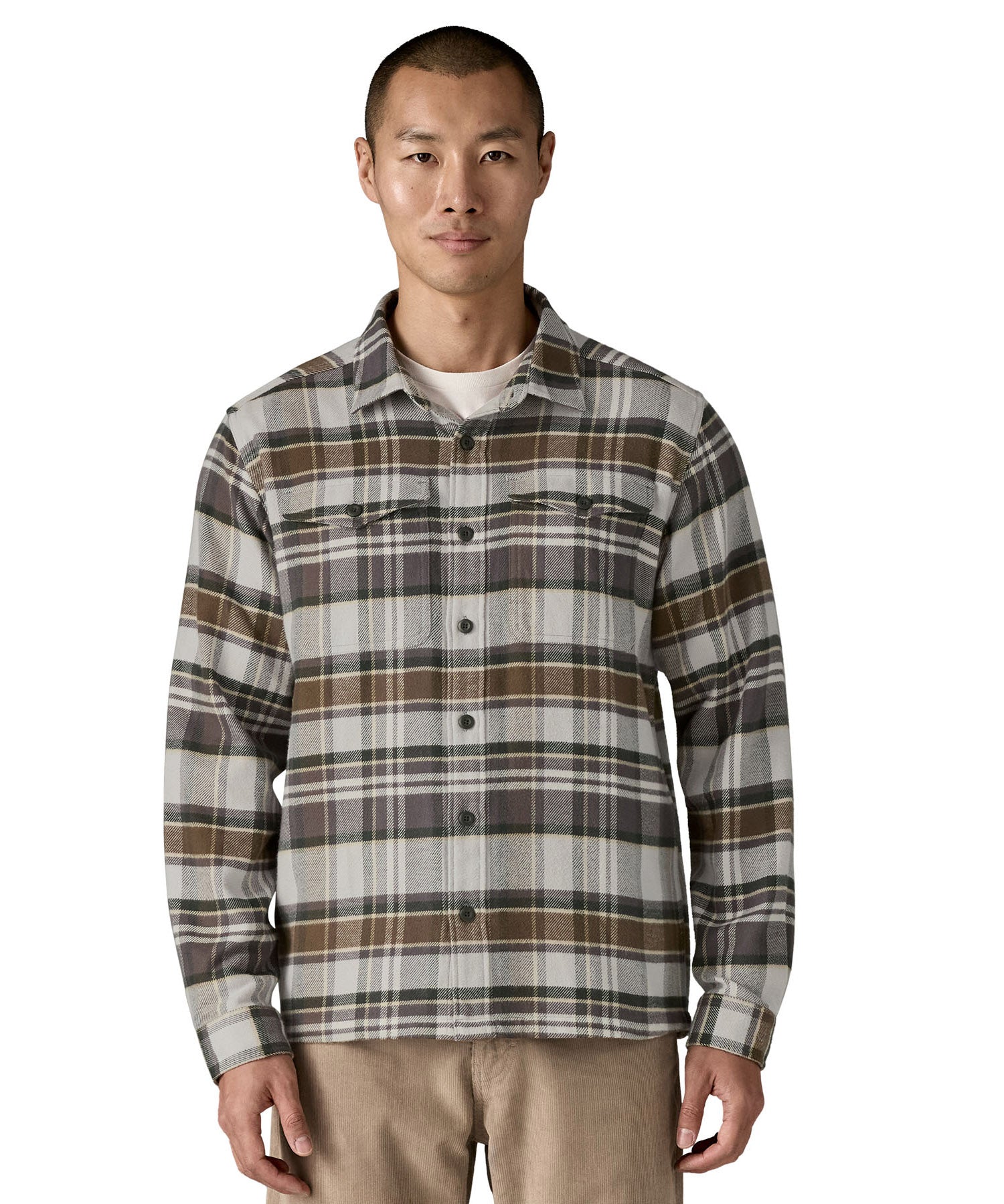  A man wearing the Patagonia fjord flannel shirt in blizzard/salt grey available at Babipur. A thick fleece in a grey and brown chequered design. Features button fasteners and 2 chest pockets 