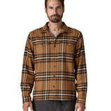  A man wearing the Patagonia fjord flannel shirt in catch deer brown available at Babipur. A thick fleece in a brown chequered design. Features button fasteners and 2 chest pockets 