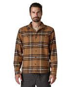  A man wearing the Patagonia fjord flannel shirt in catch deer brown available at Babipur. A thick fleece in a brown chequered design. Features button fasteners and 2 chest pockets 