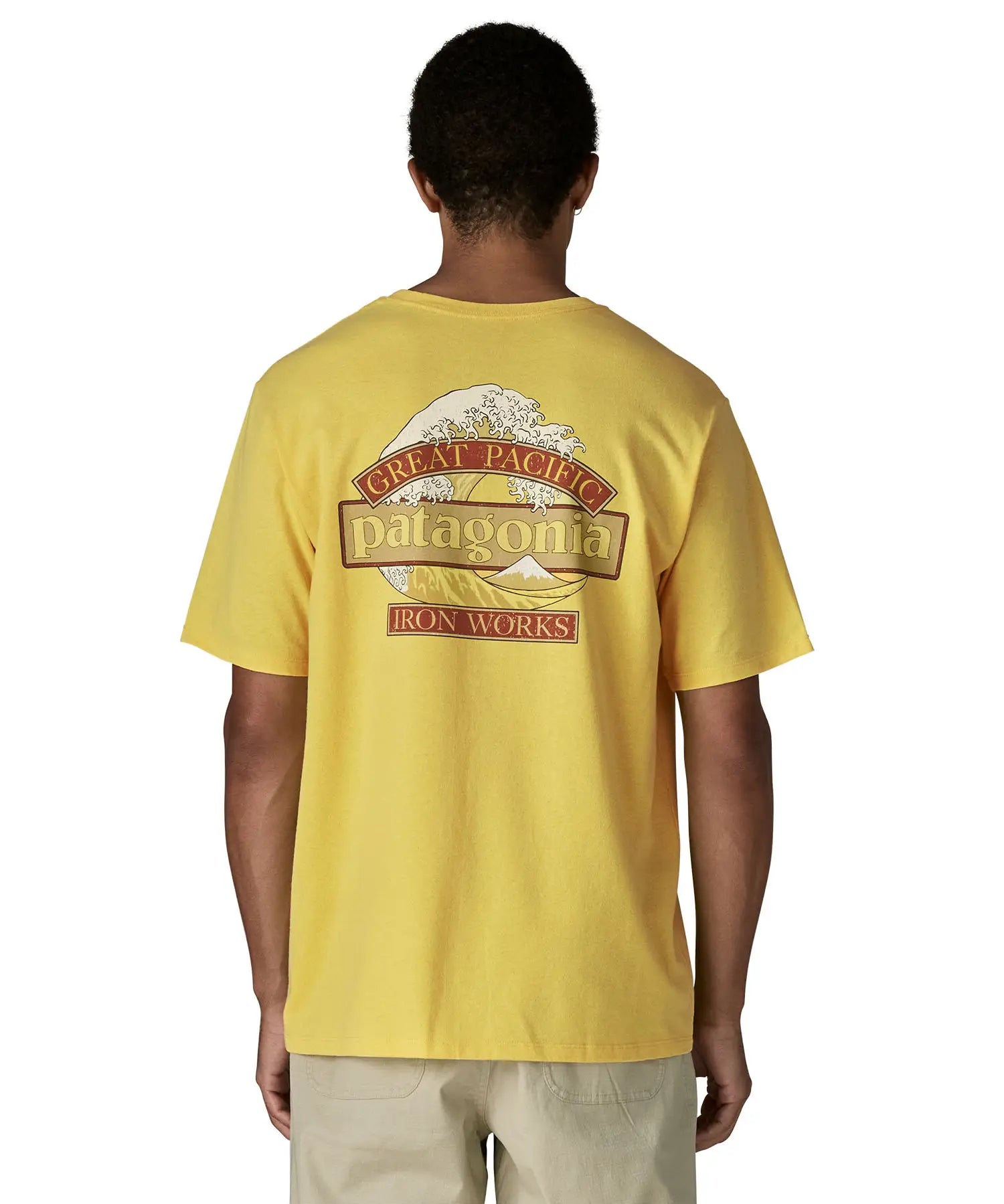 Man wearing Patagonia men's great waves responsibili short sleeve shirt in yellow with large wave graphic on upper back
