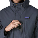Man putting a mobile phone inside the chest pocket on the Patagonia's isthmus parka jacket in dark blue 