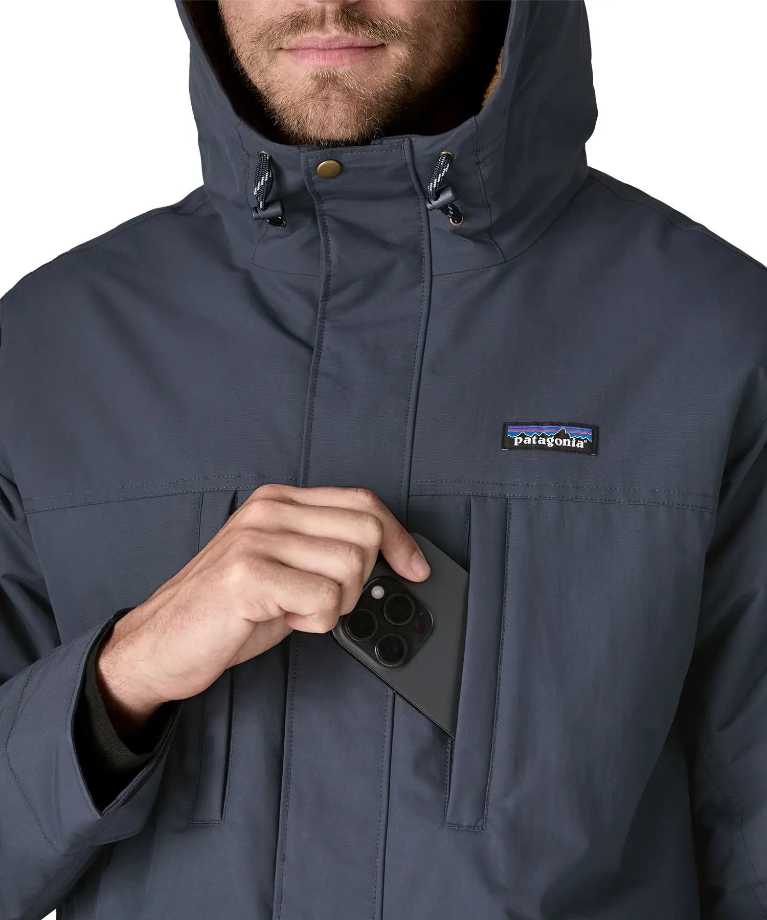 Man putting a mobile phone inside the chest pocket on the Patagonia's isthmus parka jacket in dark blue 