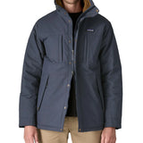 Man wearing Patagonia's isthmus parka jacket in dark blue showing the front double zips opening the jacket