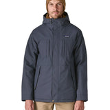 Man wearing Patagonia's isthmus parka jacket in dark blue with the front zip fully fastened. Jacket has a relaxed fit 