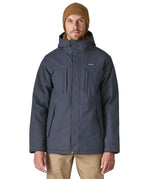 Man wearing Patagonia's isthmus parka jacket in dark blue with the front zip fully fastened. Jacket has a relaxed fit 