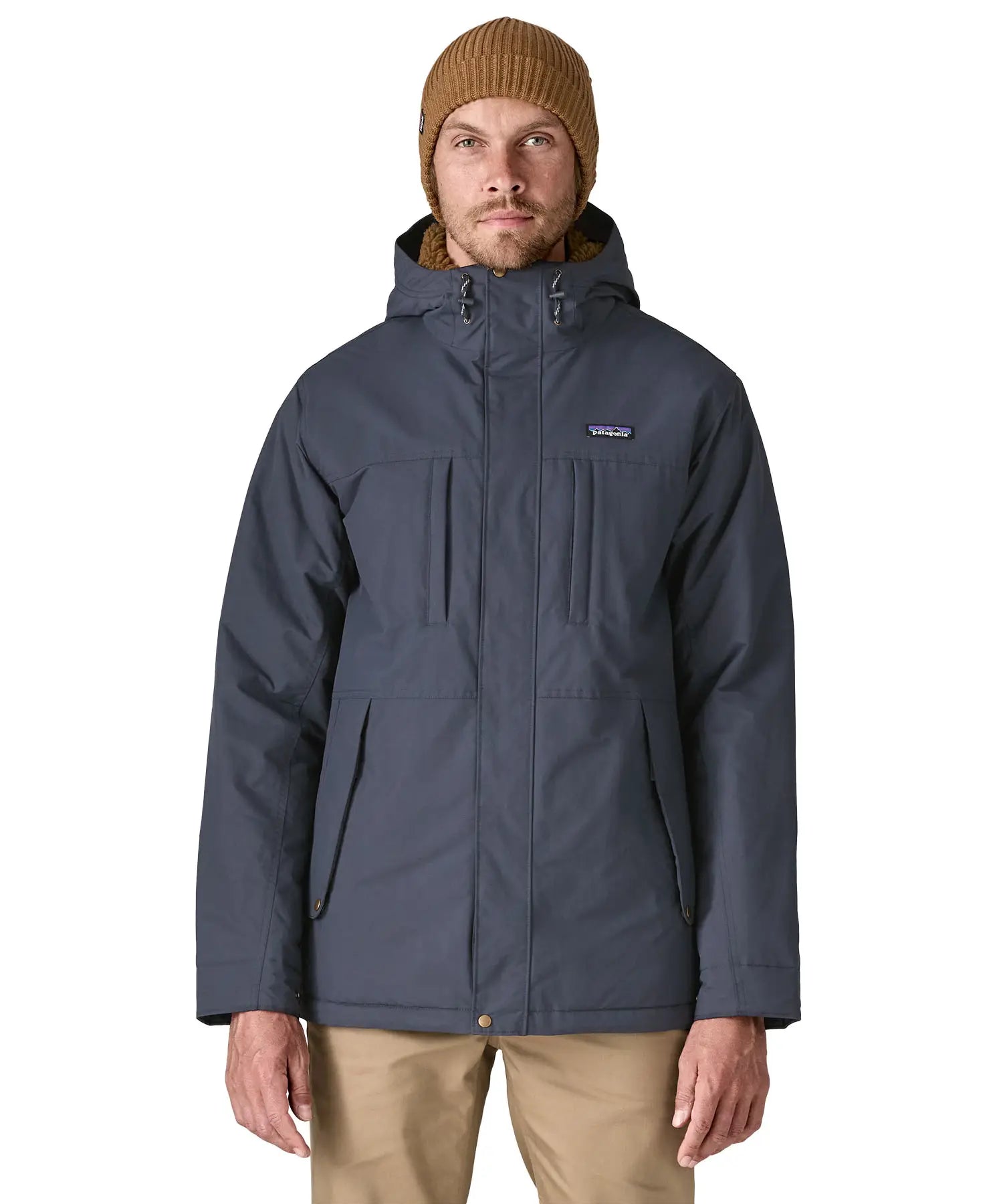 Man wearing Patagonia's isthmus parka jacket in dark blue with the front zip fully fastened. Jacket has a relaxed fit 