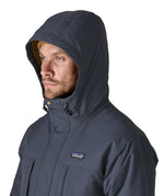 Patagonia's isthmus parka jacket in dark blue with the hood over the head showing toggles for tightness adjustment