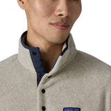 Man wearing Patagonia's lightweight synchilla snap t fleece pullover in beige showing close up of 1/4 length popper fasteners on the front