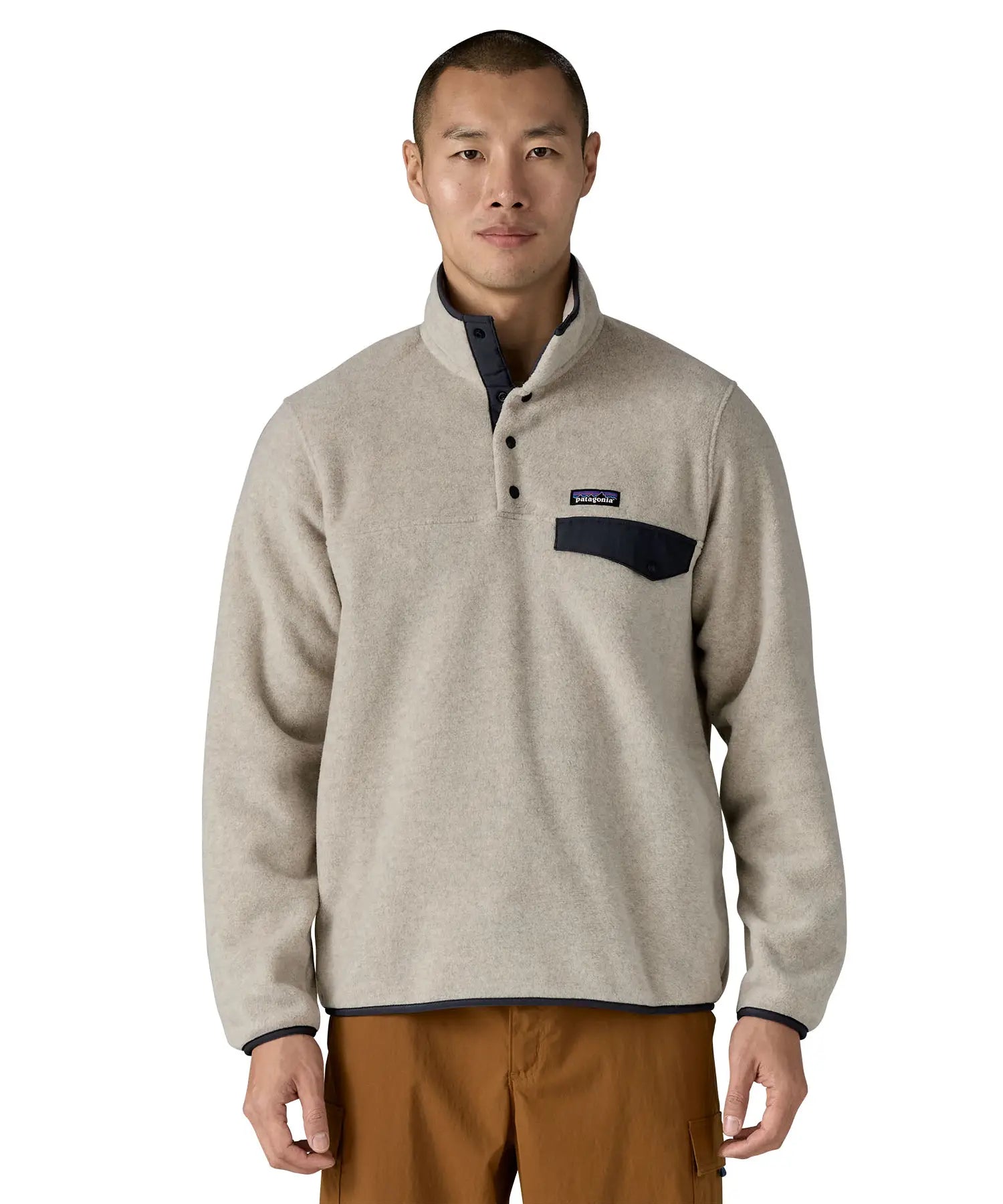 Man wearing Patagonia's lightweight synchilla snap t fleece pullover in beige with navy trim showing 1/4 length popper fasteners and chest pocket