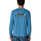 Man wearing Patagonia's men's long sleeve capilene cool t-shirt in light blue with wave logo graphic on upper back