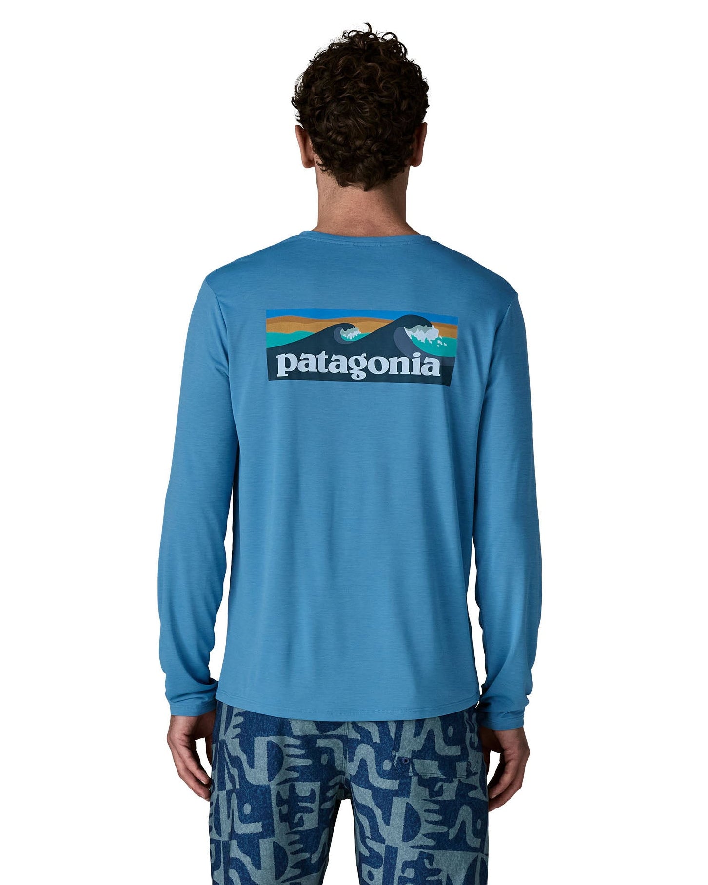 Man wearing Patagonia's men's long sleeve capilene cool t-shirt in light blue with wave logo graphic on upper back