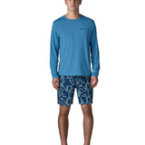 Man wearing Patagonia's men's long sleeve capilene cool t-shirt in light blue. T-shirt has a relaxed fit and sits at the hips