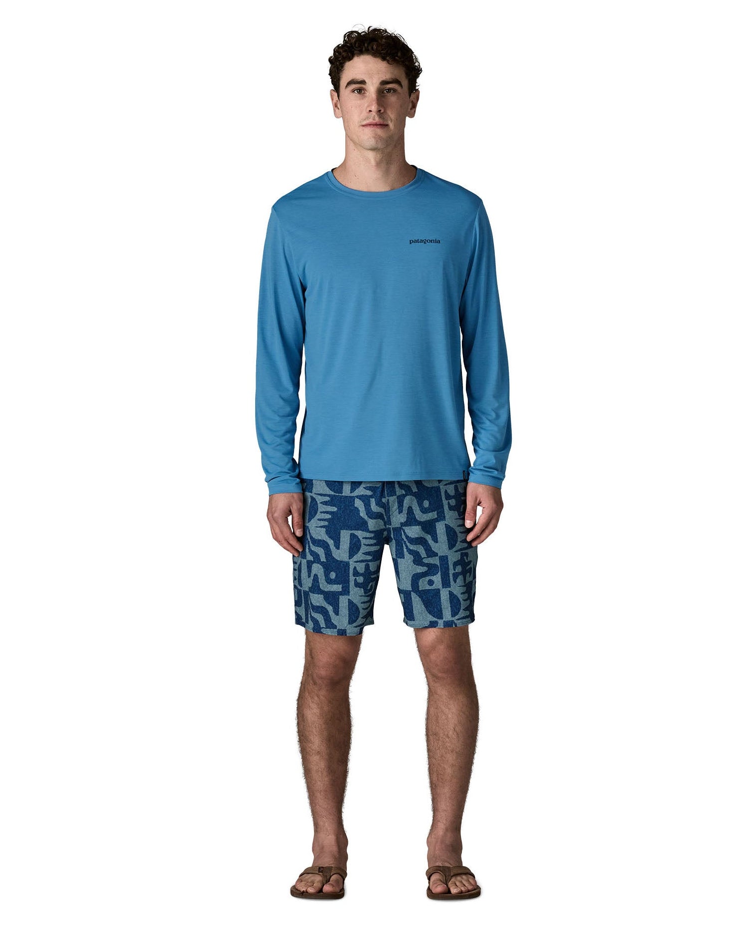 Man wearing Patagonia's men's long sleeve capilene cool t-shirt in light blue. T-shirt has a relaxed fit and sits at the hips