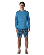 Man wearing Patagonia's men's long sleeve capilene cool t-shirt in light blue. T-shirt has a relaxed fit and sits at the hips