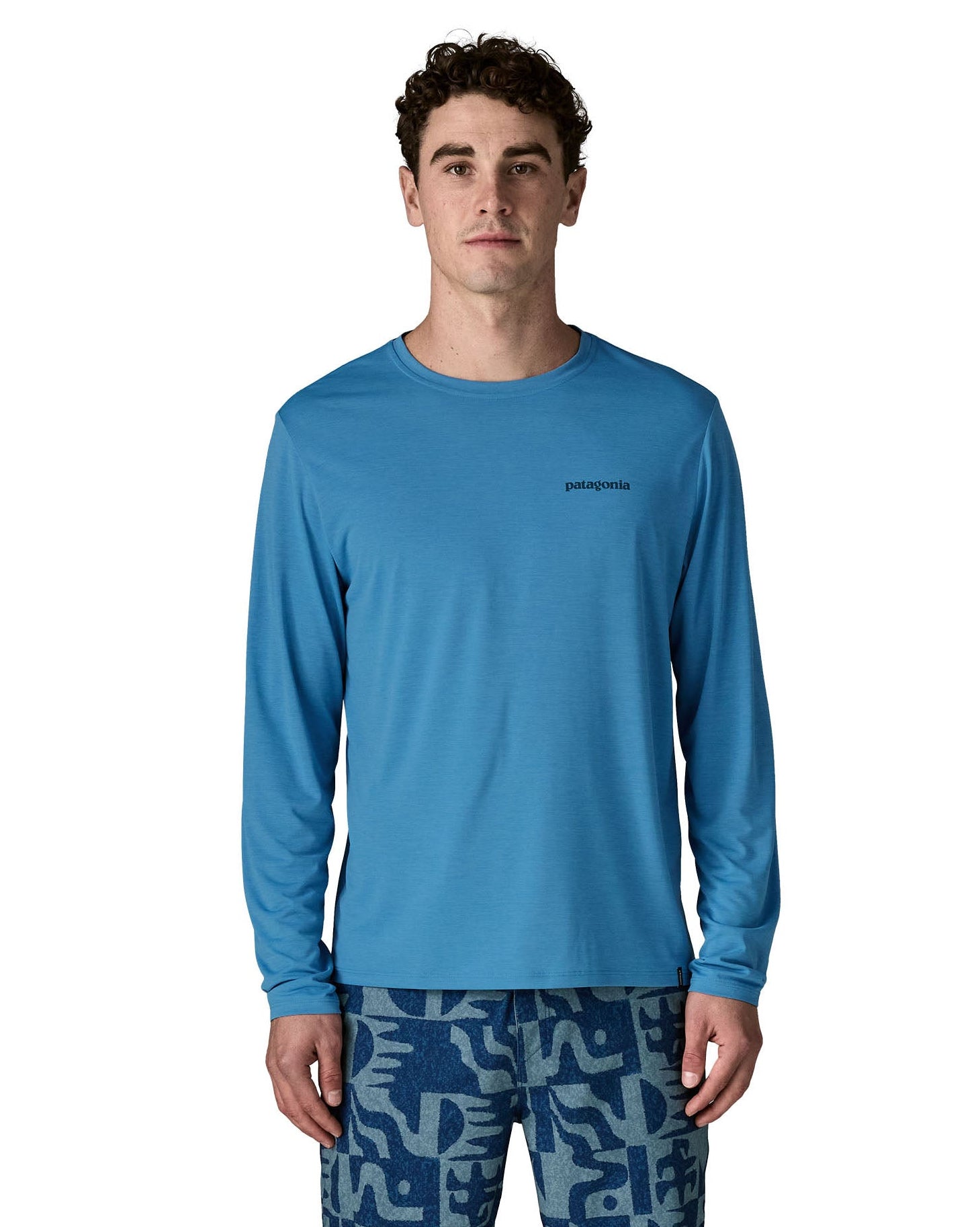 Man wearing Patagonia's men's long sleeve capilene cool t-shirt in light blue with small brand text on chest