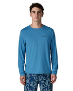 Man wearing Patagonia's men's long sleeve capilene cool t-shirt in light blue with small brand text on chest