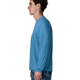 Side of man wearing Patagonia's men's long sleeve capilene cool t-shirt in light blue. T-shirt has a relaxed fit and sits at the hips