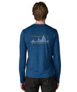 Man wearing Patagonia men's long sleeve capilene techincal t-shirt in blue showing 73 skyline inspired brand print on upper back 