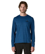 Man wearing Patagonia 73 skyline men's long sleeve capilene techincal t-shirt in blue. Top has a regular fit and sits around the hips