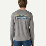 Back view of a man wearing the Patagonia Men’s Long Sleeved Capilene Cool Daily Graphic Shirt in Waters grey marl, featuring the vintage style waves graphic across the upper back.