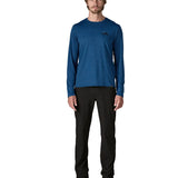 Man wearing Patagonia men's long sleeve capilene techincal t-shirt in 73 skyline clement blue. Top has a regular fit