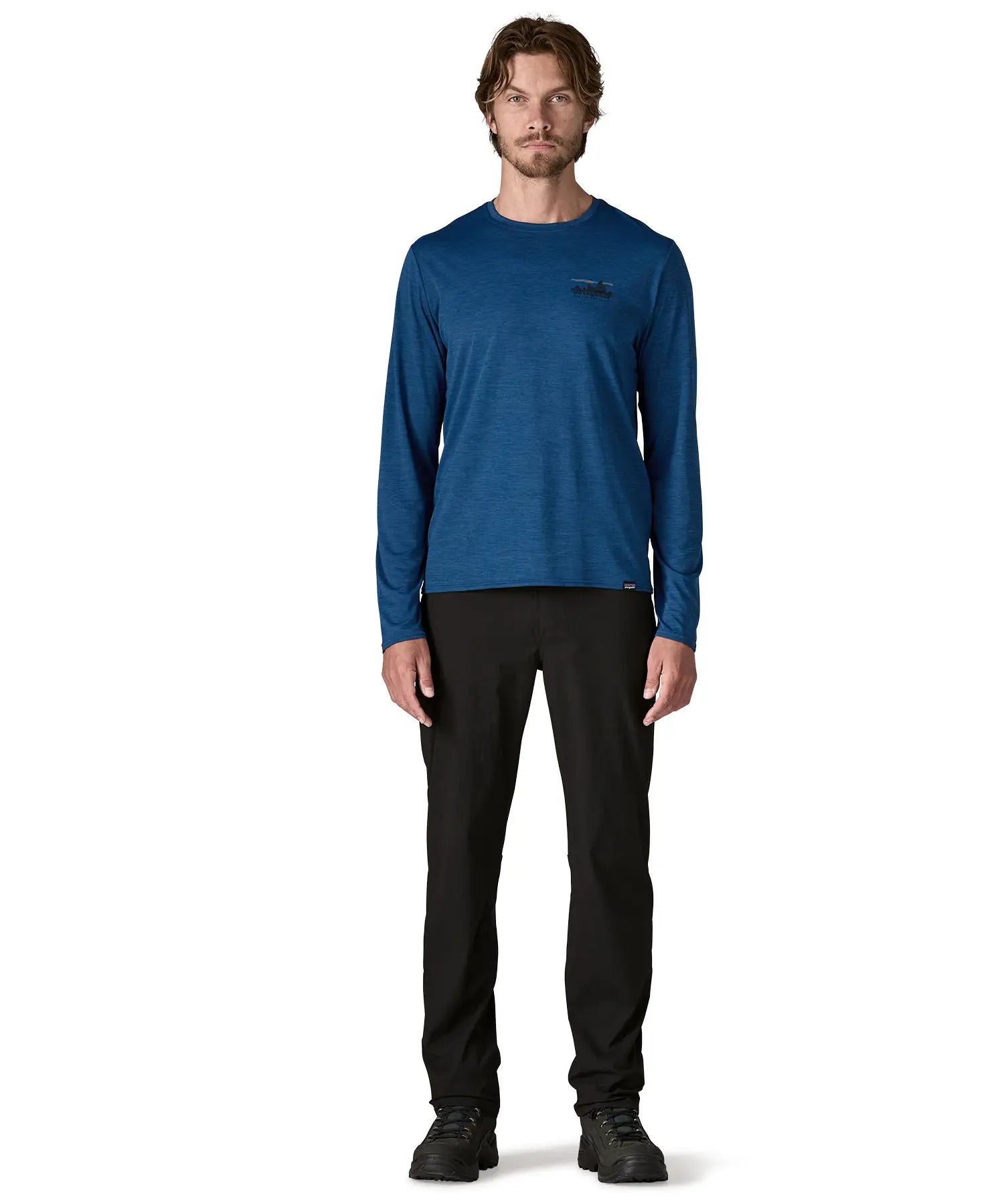 Man wearing Patagonia men's long sleeve capilene techincal t-shirt in 73 skyline clement blue. Top has a regular fit