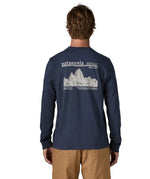 Man wearing Patagonia's long sleeve t-shirt in new navy showing a large white branded mountain range graphic on the upper back