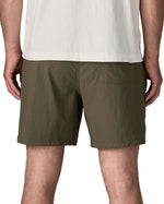 Back of man wearing Patagonia's men's outdoor everyday shorts in green. Shorts have a loose fit and sit above the knees
