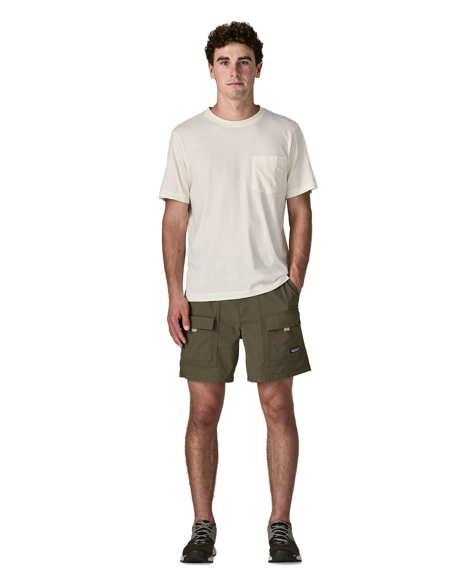 Man wearing Patagonia's men's outdoor everyday shorts in green. Shows front pockets. Shorts have a loose fit and sit over the knees