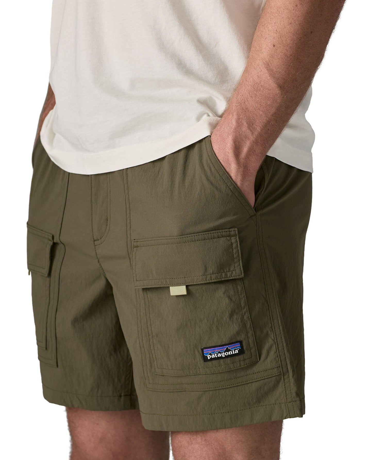 Man wearing Patagonia's men's outdoor everyday shorts in green. With hand in side pocket. Shorts have a loose fit